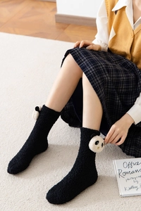 Detail of warm black coral fleece socks featuring 3D panda bear patches for home comfort