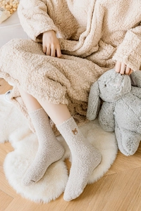 Gros plan de chaussettes douillettes en velours corail crème avec broderie ours mignon