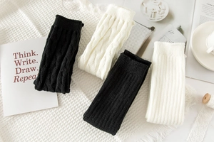 Detail of cable knit and ribbed leg warmers in black and cream white textures