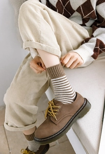 Détail de chaussettes d'hiver épaisses et chaudes à rayures marron avec chaussures rétro