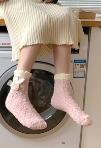 Close-up of pink coral fleece thermal socks with lace bows and decorative frill trim