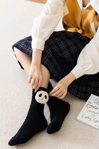 Detailed view of thick black coral fleece socks with cute 3D panda motif and soft texture