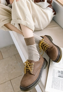 Gros plan de chaussures derby brunes avec lacets jaunes et chaussettes à rayures rétro