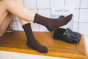 Detail of dark brown knee-high socks with ruffled edges and hollowed-out knit patterns