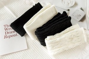 Macro detail of knit leg warmers with retro cable patterns in black and white colors