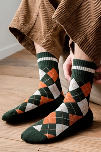 Détail de chaussettes en tricot à losanges avec motifs vert et orange et bords côtes