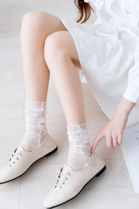 Close-up of white lace crew socks with floral embroidery and ruffle trim details