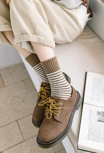 Gros plan de chaussettes rayées rétro avec des chaussures en cuir marron et un pantalon velours