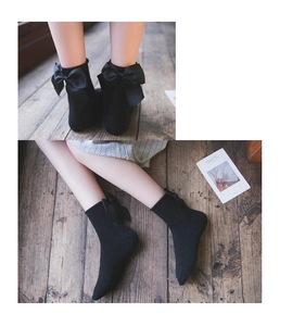 Dettaglio di calze nere in cotone con grande fiocco di raso sul tallone in stile Lolita