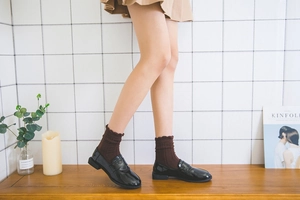 Detail of dark coffee frilly trim socks paired with glossy black patent loafers