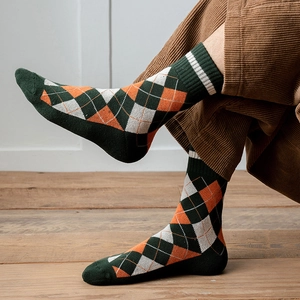 Gros plan de chaussettes à losanges vert forêt et orange portées avec un pantalon