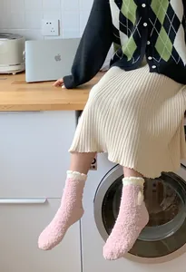 Detail of pink coral fleece socks featuring ruffled cuffs and white floral accents