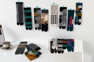 Artistic Tabi socks with diverse geometric patterns displayed on a minimalist wall and table