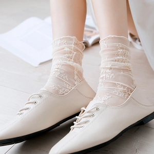 Macro detail of cream lace mesh socks with vintage pattern and sheer texture