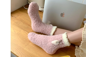 Detailed view of pink coral fleece thermal socks with fluffy white cuffs and cute label