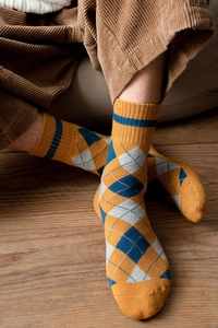 Gros plan sur des chaussettes en maille à losanges portées avec un pantalon en velours