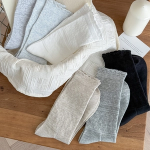 Close-up of assorted lace-trimmed mid-calf socks with waffle texture on a wooden surface