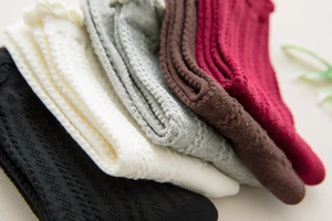 Detail showing various colors of knitted cotton socks with intricate hollow weave patterns