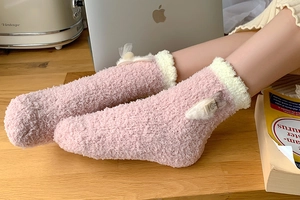 Close-up of pink coral fleece socks featuring plush white trim and 3D rabbit ears