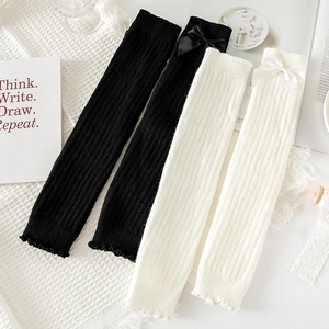 Detail of knit leg warmers with ribbon bows and ribbed texture on waffle fabric