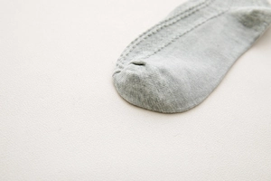 Detail of grey cotton sock toe showing fine knitting texture and smooth flat seam