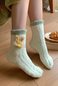 Detail of cute cream coral fleece socks with 3D bunny patch and green ruffle cuffs
