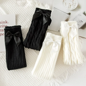 Detail of cable knit leg warmers with silk bows in black and cream for JK uniforms