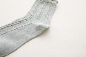 Macro shot showing soft vertical rib knit texture and heel detail of light gray cotton socks
