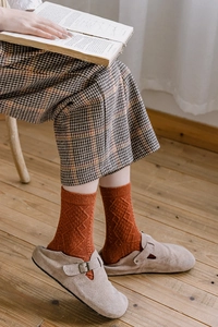 Close-up of caramel orange wool blend socks with diamond texture and suede clogs