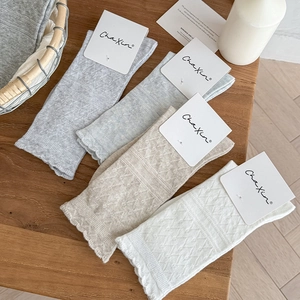 Detailed view of four pairs of floral knit cotton socks in soft pastel colors and wavy cuffs