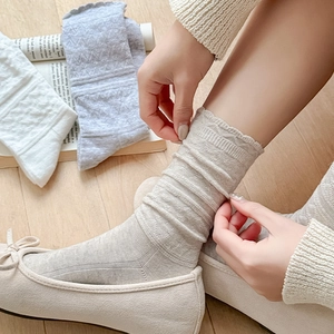 Close-up of knit texture and wavy edges on beige, white, and grey ruffle crew socks