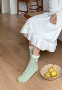Close-up of thick light green coral fleece home socks with cute plush rabbit patch detail