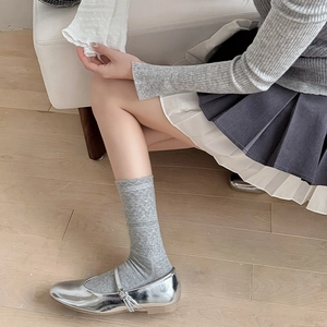 Detail of light gray argyle patterned crew socks paired with silver Mary Jane shoes