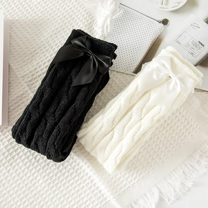 Detail of cable knit leg warmers featuring large satin bows for a sweet lolita style