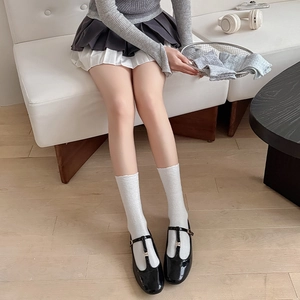 Close-up of white crew socks with delicate lace trim paired with Mary Jane shoes