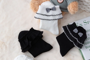 Detail of white and black Lolita socks with ruffled lace and plaid bow decoration