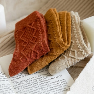 Detail of wool socks in red, yellow, and white with a textured diamond pattern
