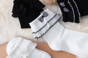 Close-up of Lolita lace socks with checkered bows and ruffles on soft wool background