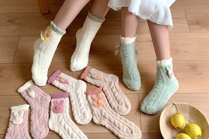 Detail of coral fleece socks with cute cartoon rabbit patches and cable knit texture