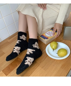 Detailed texture of thick black coral fleece socks with brown bear pattern and fuzzy material