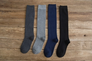 Flat lay of four pairs of high-knee cotton socks in black, grey and navy blue colors