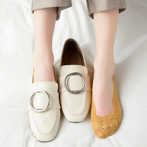 Close-up of yellow lace floral no-show socks worn with stylish buckle loafers
