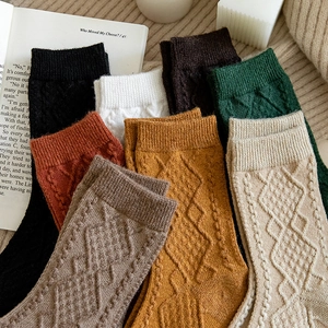 Detailed close-up of argyle knit pattern and ribbed cuffs on stacked winter wool socks