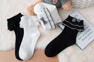Detailed view of Lolita style knee-high socks with lace ruffles and plaid bow accents