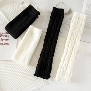 Knit leg warmers in black and white with cable knit texture and ruffle trim details