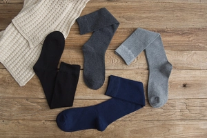 Detail view of four pairs of high-quality wool socks on a rustic wooden background