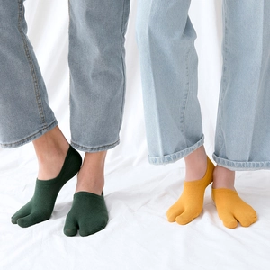 Detail of low-cut two-toe socks in dark green and ginger yellow with soft knit texture