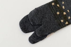 Close-up of dark grey Tabi socks featuring beige polka dots on the split toes