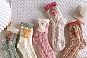 Close-up of five pairs of thick coral fleece winter socks with 3D rabbit patches