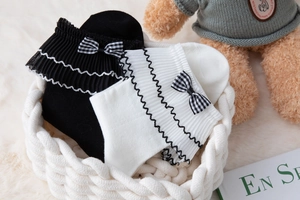 Detail of white and black Lolita socks with ribbon bows and ruffled cuffs in a basket